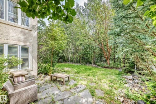 Stone patio with a grass lawn and surrounding mature trees - 417 Caldwell Place Nw, Edmonton, AB 
