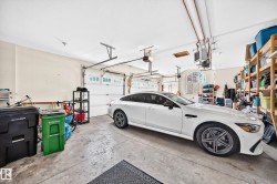 3 car garage with concrete flooring, two overhead garage doors, and built-in shelving - 