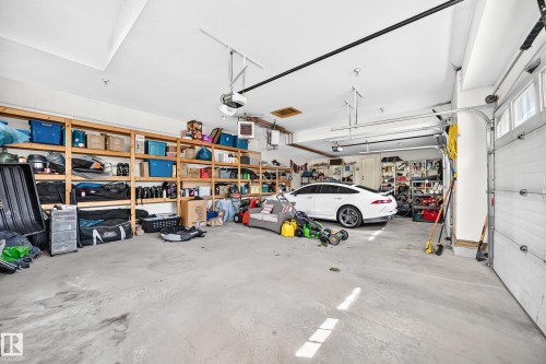 Spacious garage featuring concrete flooring and extensive built-in wooden shelving for ample storage - 417 Caldwell Place Nw, Edmonton, AB 