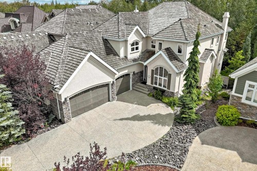 Stucco exterior featuring stone accents, a multi-car driveway, a two-car garage, and a peaked roof - 417 Caldwell Place Nw, Edmonton, AB 