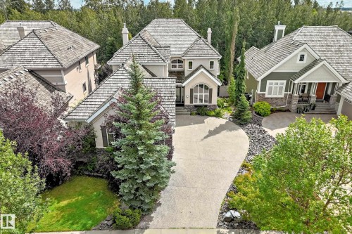 Multi-level pitched roof, curved concrete driveway, mature landscaping, stone accents, and varied exterior finishes - 417 Caldwell Place Nw, Edmonton, AB 