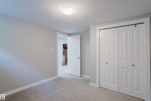 Recessed lighting fixture, light gray wall paint, light-colored carpet, white bi-fold closet doors, and white interior door - 4708 106 Avenue Nw, Edmonton, AB 