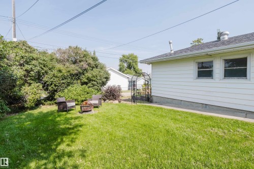Expansive green lawn with mature perimeter shrubbery and a white siding exterior - 4708 106 Avenue Nw, Edmonton, AB 