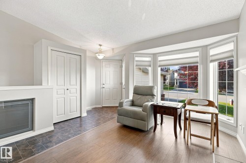 Light wood-finish flooring, a bay window with multiple panes, a built-in fireplace, and a light-toned front door - 30 Belfry Fairway Crescent, Stony Plain, AB 