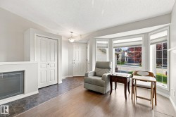 Light wood-finish flooring, a bay window with multiple panes, a built-in fireplace, and a light-toned front door - 
