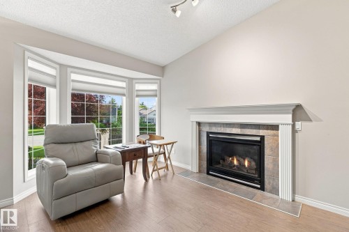 Vaulted ceiling, bay windows, fireplace with tile surround, wood-finish flooring, and recessed lighting - 30 Belfry Fairway Crescent, Stony Plain, AB 
