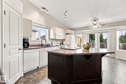 Kitchen featuring light-toned cabinetry, a dark-toned island with a light-toned countertop, a ceiling fan, and patio doors - 