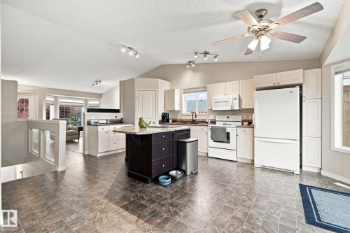 Spacious kitchen featuring white appliances, a center island with a dark wood-finish base, ample cabinetry, and a ceiling fan - 30 Belfry Fairway Crescent, Stony Plain, AB 