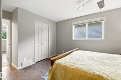 Wood-finish flooring, white trim, sliding closet doors, window with roller shades, and a ceiling fan - 