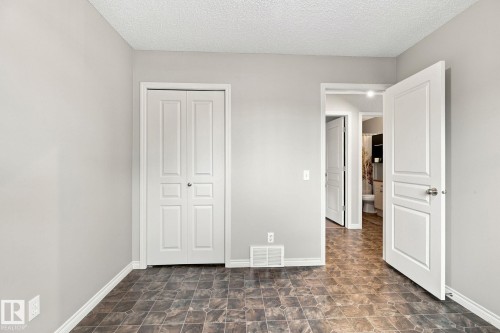 Textured ceiling, neutral wall paint, white trim, bifold closet doors, and wood-finish flooring - 30 Belfry Fairway Crescent, Stony Plain, AB 