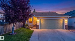 Two-car garage with paneling, brick veneer accents, and sconce lighting - 