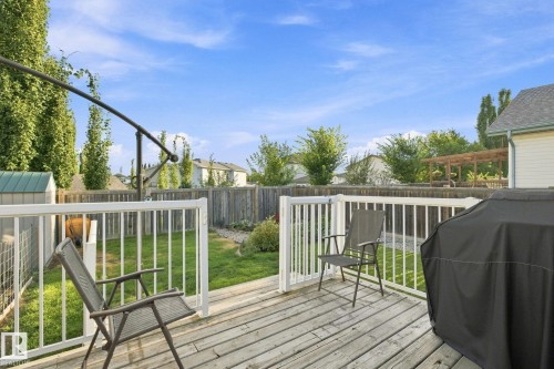 Deck with white railing and gate, leading to a fenced backyard with a manicured lawn - 30 Belfry Fairway Crescent, Stony Plain, AB 