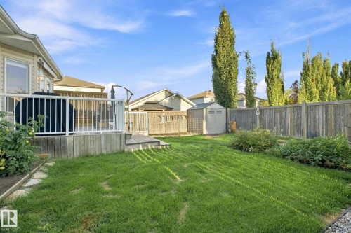 Expansive backyard featuring a wood deck with white railings, a green lawn, a storage shed, and a privacy fence - 30 Belfry Fairway Crescent, Stony Plain, AB 