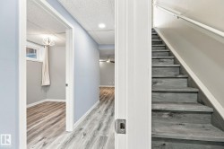 Wood-finish stairs with white handrail, recessed lighting, and wood-finish flooring throughout - 