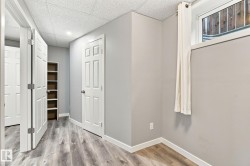 Wood-finish flooring, drop ceiling with recessed lighting, built-in shelving, white paneled doors, and a window providing natural light - 