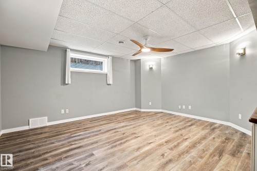 Wood-finish flooring, drop ceiling, modern ceiling fan, wall sconces, and a window - 30 Belfry Fairway Crescent, Stony Plain, AB 