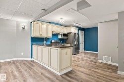 Kitchen with cream cabinetry, stainless steel appliances, and wood-finish flooring - 
