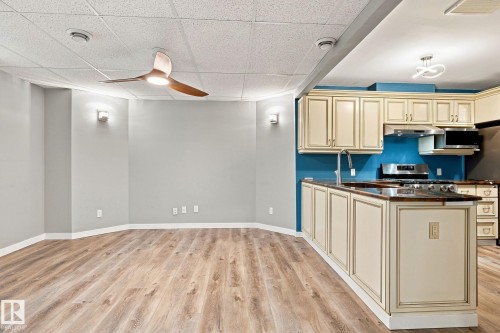Wood-finish flooring, cream kitchen cabinetry, stainless steel appliances, modern ceiling fan, and contemporary light fixtures - 30 Belfry Fairway Crescent, Stony Plain, AB 
