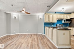 Wood-finish flooring, cream kitchen cabinetry, stainless steel appliances, modern ceiling fan, and contemporary light fixtures - 