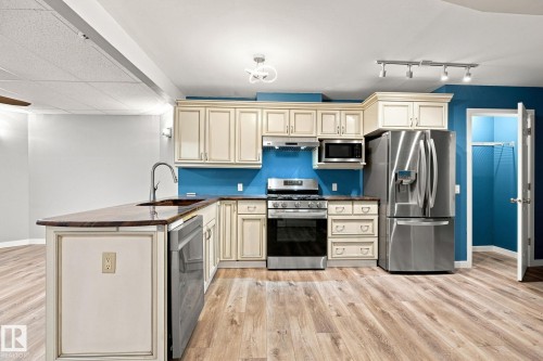 Kitchen featuring wood-finish flooring, stainless steel appliances, cream cabinetry, a built-in microwave, and a double-door refrigerator - 30 Belfry Fairway Crescent, Stony Plain, AB 