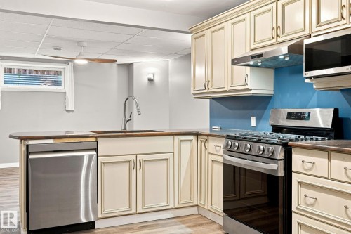 Kitchenette featuring cream-painted cabinetry, stainless steel dishwasher, stainless steel gas range, and a drop ceiling with recessed lighting - 30 Belfry Fairway Crescent, Stony Plain, AB 