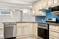 Kitchenette featuring cream-painted cabinetry, stainless steel dishwasher, stainless steel gas range, and a drop ceiling with recessed lighting - 
