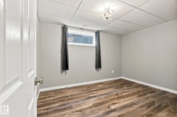 Wood-finish flooring, light gray wall paint, and a window with blinds - 