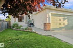 Front exterior featuring light-toned siding, a bay window, an attached garage, a concrete driveway, and a fenced side yard - 