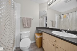 Wood-finish flooring, light tone cabinetry with brushed nickel hardware, and dark countertop with integrated sink - 