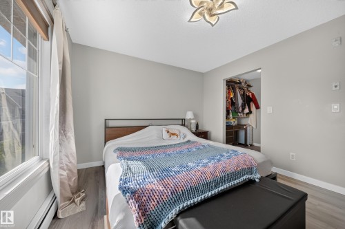 Wood-finish flooring, white trim, and a built-in closet with an open doorway - #419 4407 23 St Nw, Edmonton, AB 