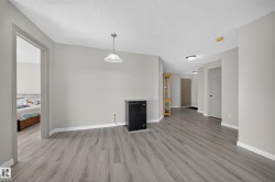 Open-concept living space featuring gleaming wood-finish flooring throughout, white painted walls, and abundant natural light from multiple windows - 