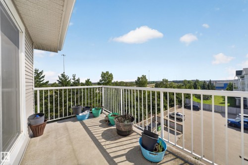 Concrete balcony with white metal railing and a sliding glass door - #419 4407 23 St Nw, Edmonton, AB 