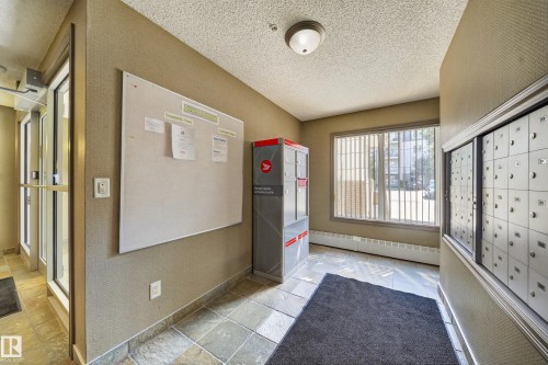 Tiled flooring, large window with blinds, wall-mounted mailboxes, and an interior bulletin board - #419 4407 23 St Nw, Edmonton, AB 