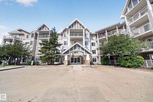 Multi-story building with gabled roof lines, multiple balconies, and an asphalt parking area - #419 4407 23 St Nw, Edmonton, AB 