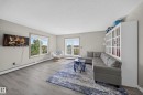 Wood-finish flooring, light grey wall paint, multiple windows, and a built-in display cabinet - #419 4407 23 St Nw, Edmonton, AB 