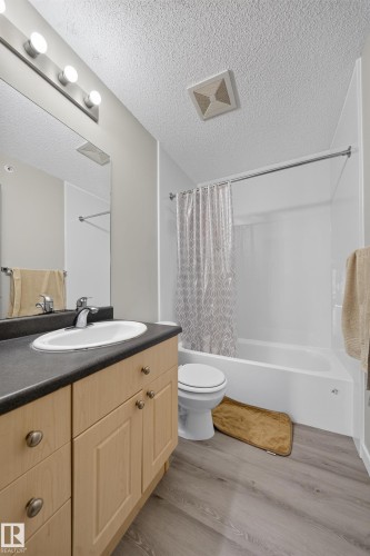 Light wood-finish vanity with a dark countertop and integrated sink - #419 4407 23 St Nw, Edmonton, AB 
