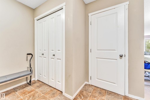 Tiled flooring with a neutral color palette, paneled interior doors, and bi-fold closet doors - #225 111 Watt Cm Sw, Edmonton, AB 