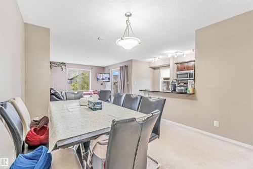 Dining area with ceiling-mounted light fixture, carpeted flooring, and a clear line of sight to the kitchen - #225 111 Watt Cm Sw, Edmonton, AB 
