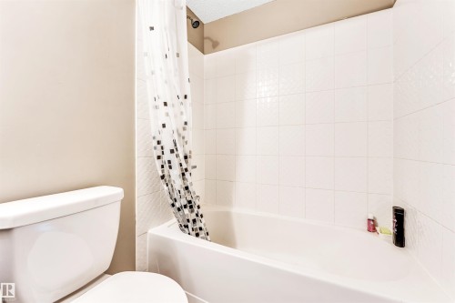 White tile surround shower-over-tub combination with a dark-finished showerhead - #225 111 Watt Cm Sw, Edmonton, AB 
