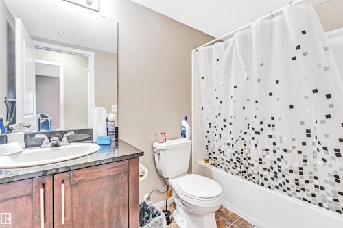 Vanity with dark wood-finish cabinetry, integrated sink, and dark countertop - #225 111 Watt Cm Sw, Edmonton, AB 