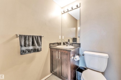 Dark wood-finish vanity with a contrasting countertop, integrated sink, and wall-mounted mirror - #225 111 Watt Cm Sw, Edmonton, AB 
