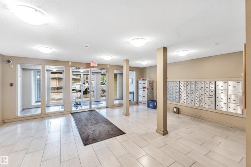 Entryway featuring white tile flooring, recessed lighting, glass-paneled doors, and individual mailboxes - #225 111 Watt Cm Sw, Edmonton, AB 