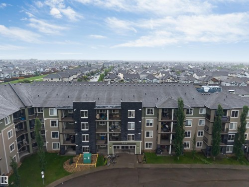 Multi-story building featuring balconies, dark gray roof, and a mix of exterior finishes - #225 111 Watt Cm Sw, Edmonton, AB 