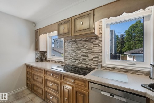 Light wood cabinetry, tile backsplash, built-in cooktop, integrated dishwasher, and corner sink - 12916 63 Street Nw, Edmonton, AB 