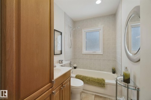 Integrated bathtub with tiled surround, recessed lighting, and a frosted window - 12916 63 Street Nw, Edmonton, AB 