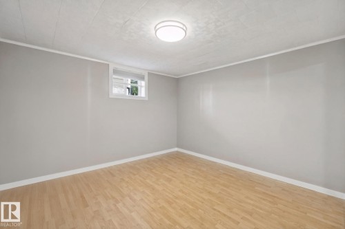 Light wood-finish flooring, neutral gray walls, white trim, and a flush-mount ceiling light - 12916 63 Street Nw, Edmonton, AB 