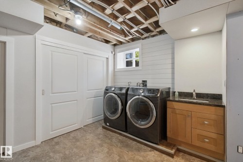 Laundry area featuring a utility sink with a stone countertop, wood-finish cabinetry, and shiplap wall paneling - 12916 63 Street Nw, Edmonton, AB 