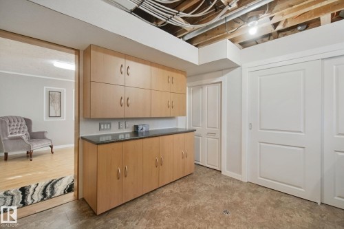 Wood-finish cabinetry with dark countertop, multiple storage closets, and light-toned flooring - 12916 63 Street Nw, Edmonton, AB 