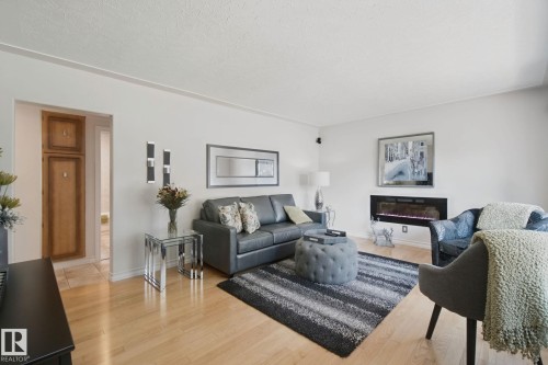 Hardwood flooring throughout, recessed wall fireplace, built-in cabinetry, and modern wall sconces - 12916 63 Street Nw, Edmonton, AB 