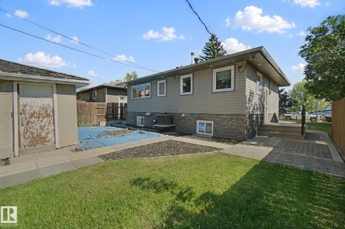 Exterior featuring grey siding, a stone veneer foundation, white-framed windows, and a paver walkway - 12916 63 Street Nw, Edmonton, AB 